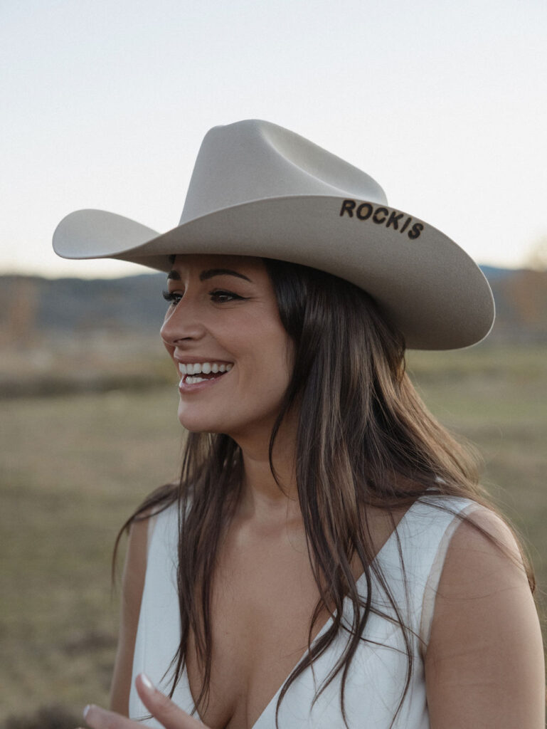 Beautiful bride rocking a cowboy hat and her Jackson Hole elopement hair and makeup